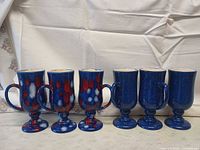 Six ceramic pedestal mugs in two patterns on tabletop