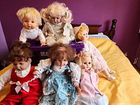 Group shot of six vintage dolls on bed showing size and outfits