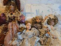 Four porcelain dolls seated together displaying sizes and outfits