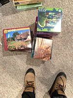 Stack of jigsaw puzzle boxes showing cottage, deer and landscape themes
