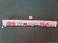 Front view showing all eight earring pairs lined on fabric strip with size reference coin