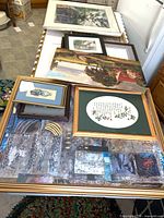 Stack of multiple framed artworks showing variety of pieces