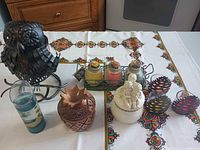 Group shot showing all items: metal owl lantern, rack with three jar candles, wooden pineapple box, ceramic cherub trinket box, tall glass candle, four pinecone tealight holders