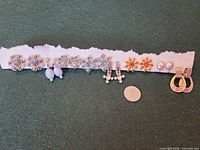 Front view of all eight earring pairs on fabric strip with coin for scale