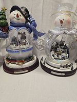 Both snowman snow globes side by side
