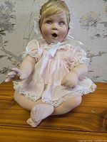 Front view porcelain baby doll seated on wooden surface