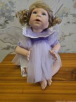 Full view of doll seated showing lavender dress, wings, and halo