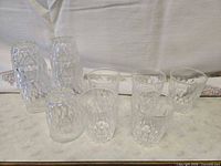 Group of small pressed-glass tumblers, some upright, some inverted