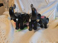 Front view of three black resin elephant candle holders with glass cups and tealight