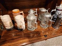 All six steins on shelf: four glass, two ceramic