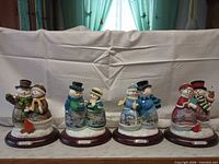 Front view of all four snowman couple figurines lined up
