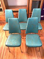 Front view of all five teal vinyl chairs showing upholstery and chrome legs