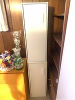 Full view of tall off-white metal cabinet showing two stacked doors and handles