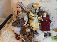 All four porcelain dolls seated together with teddy bear