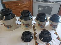 Four ceramic canisters with floral design and black enamel lids