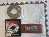 Overview showing all four items: glass Santa plate, silver wreath, boxed doily, Last Supper plaque