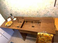 Top view of sewing cabinet showing fold-top, recessed machine platform and surface wear