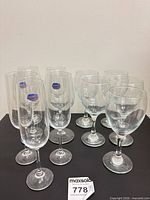 Group of 12 stemmed glasses; three champagne flutes with Ocean stickers and nine wine glasses
