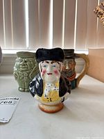 Front view of bust-form jug; other two jugs visible in background