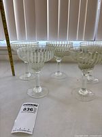 Five striped light green margarita glasses on table with measurement tape visible