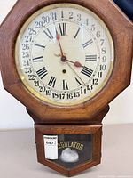 Front view of Arthur Pequegnat regulator clock showing full case, dial, pendulum and REGULATOR glass