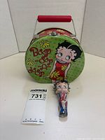 Front view of round metal lunch box with lip gloss candy figure