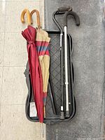 Two umbrellas and two canes displayed in a boot tray