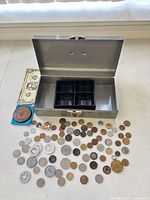 Open metal cash box with plastic tray, two-dollar bill, medallion on cloth, scattered coins
