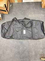 Full view of entire black duffel bag with handles and shoulder strap visible, shows size and overall condition
