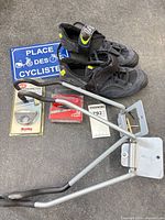 Overview showing shoes, packaged inclinometer, packaged tail light, two bike hooks, blue sign