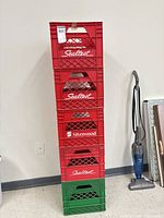 Stack of five plastic milk crates, four red and one green