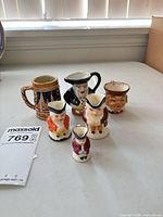 Group shot of six miniature ceramic Toby jugs and souvenir stein