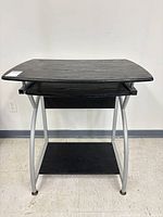 Front view of black computer desk with keyboard tray and lower shelf