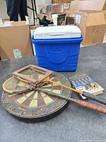 Group shot showing cooler, dartboard, racquets, racquet press, book