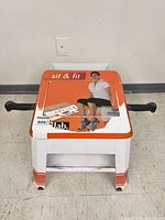 Top view showing Sit & Fit branding, orange top panel and black handles