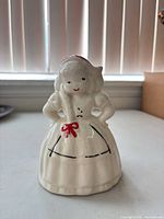 Front view of cream glazed ceramic lady planter showing facial features, bow, dress detailing