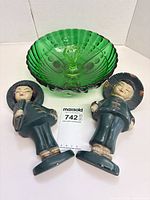 Green pressed glass bowl with two chalkware Asian figurines