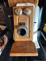 Front view showing complete oak wall telephone with bells, transmitter, receiver and shelf