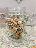 Glass jar filled with assorted costume jewelry viewed from front