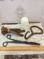 all items laid out: four spikes, insulator, coal tongs, hook tool with ruler for scale