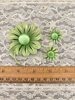 front view of brooch and earrings on lace fabric with ruler