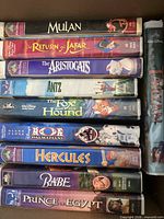 Stack of ten VHS tapes showing titles on spines inside box