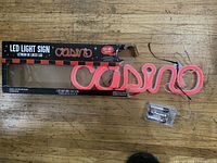 LED casino sign, battery pack and original box displayed on wood floor