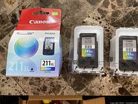 Boxed Canon CL-211XL cartridge and two sealed Canon CL-241XL cartridges on tabletop