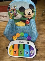 Mickey Mouse foam chair with Baby Einstein piano and bead rattle in front