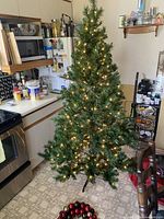 Pre-lit artificial Christmas tree and loose ornaments on floor