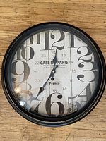Front view of round Cafe de Paris wall clock showing face design and condition