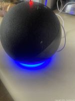 Front angled view of spherical Amazon Echo showing fabric exterior and illuminated LED ring