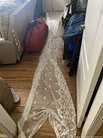 Full view of one long lace panel laid out on floor showing overall length and pattern