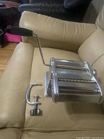 Full view of pasta machine with crank and clamp on chair